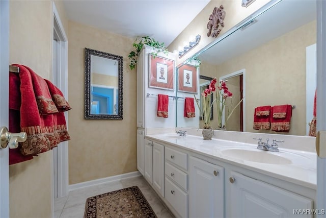 bathroom with double vanity, baseboards, a sink, and tile patterned floors