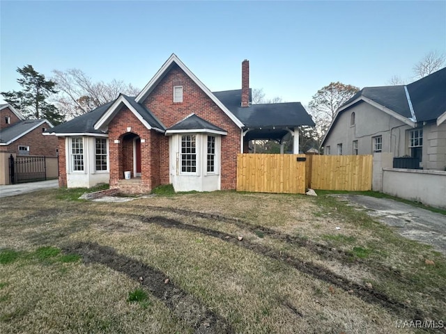 view of front of home with a gate, a chimney, fence, and brick siding