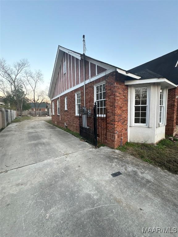 property exterior at dusk with brick siding and fence