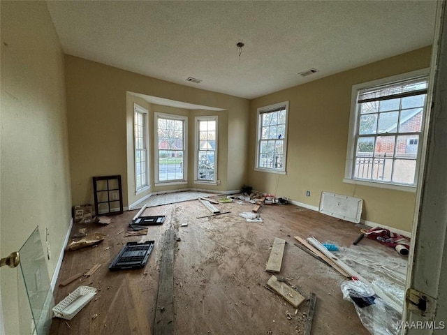 spare room featuring a textured ceiling, visible vents, and a healthy amount of sunlight