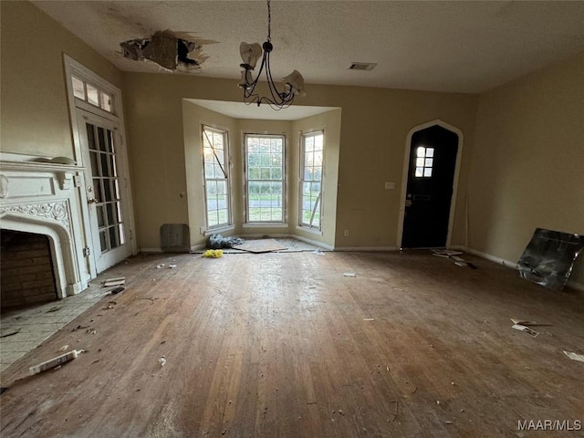 interior space with baseboards, wood-type flooring, visible vents, and a notable chandelier