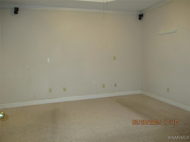 carpeted spare room featuring baseboards and crown molding