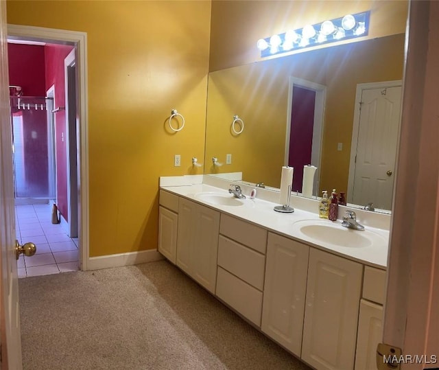 full bathroom with double vanity, baseboards, a sink, and carpet flooring