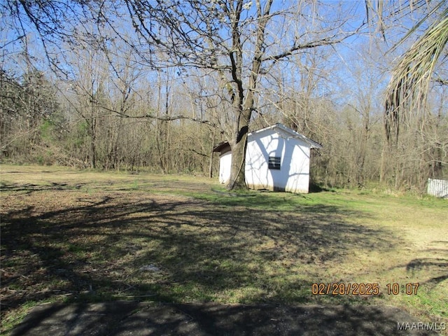 view of yard featuring an outdoor structure, a view of trees, and a storage unit