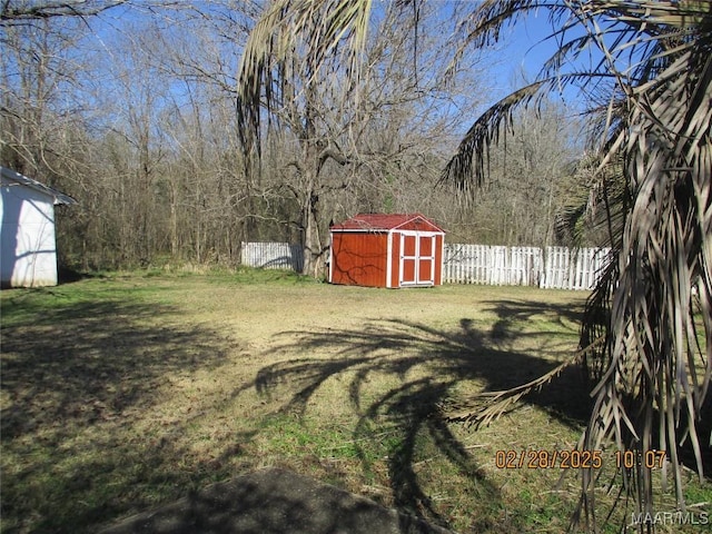 view of yard featuring an outbuilding, fence, and a storage shed