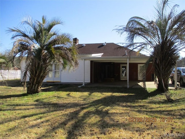 back of property with a chimney, a lawn, a patio area, and fence