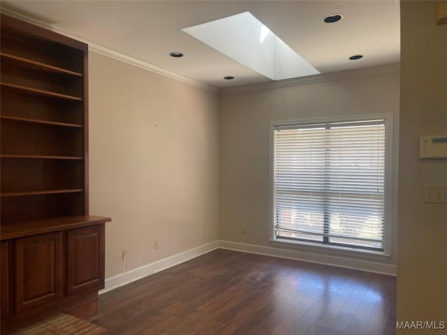 unfurnished room featuring a skylight, baseboards, dark wood finished floors, ornamental molding, and recessed lighting