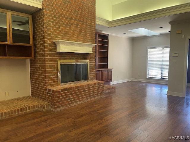 unfurnished living room featuring a skylight, a fireplace, baseboards, dark wood finished floors, and crown molding