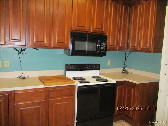 kitchen with brown cabinetry, black microwave, light countertops, and electric range oven