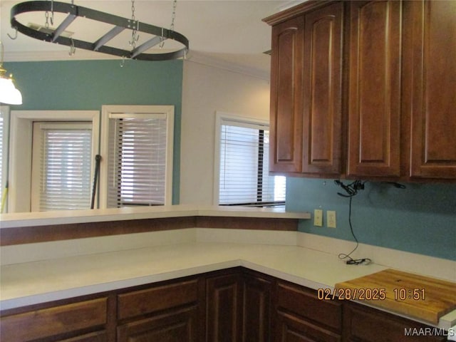 kitchen with light countertops, crown molding, and dark brown cabinets