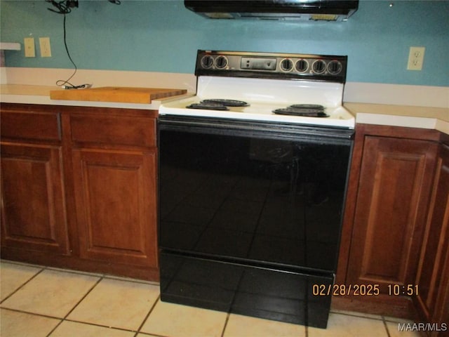 kitchen with light tile patterned floors, range hood, light countertops, and electric range oven