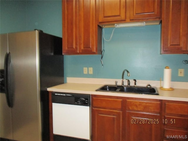 kitchen featuring a sink, stainless steel refrigerator with ice dispenser, dishwasher, and light countertops