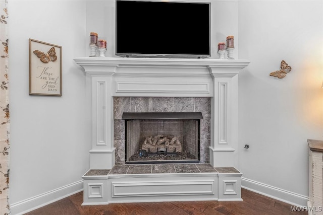 room details featuring a fireplace, baseboards, and wood finished floors