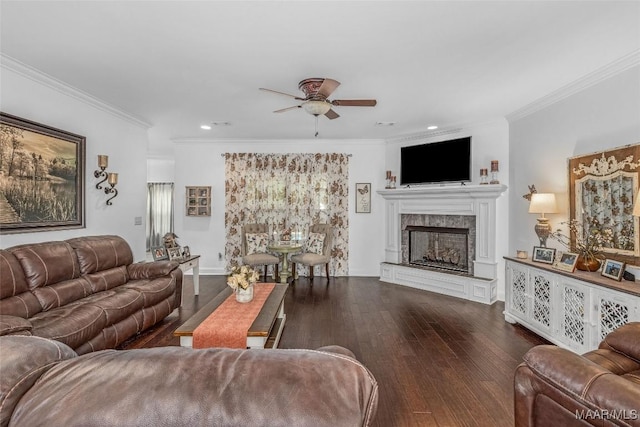 living area featuring ornamental molding, dark wood finished floors, a tiled fireplace, and a ceiling fan