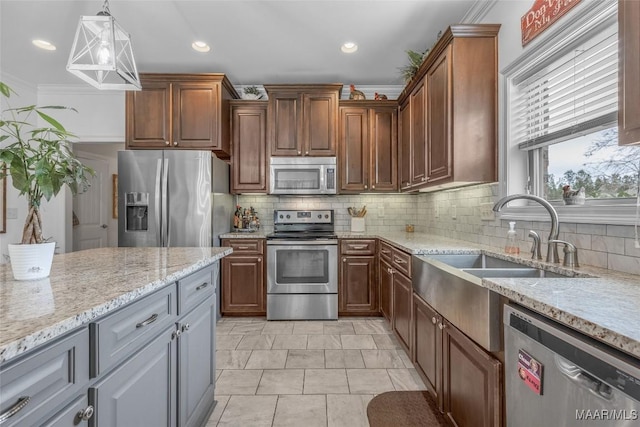 kitchen with stainless steel appliances, a sink, light stone countertops, tasteful backsplash, and decorative light fixtures