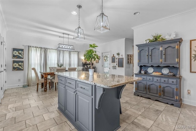 kitchen with a kitchen island, ornamental molding, hanging light fixtures, light stone countertops, and gray cabinets