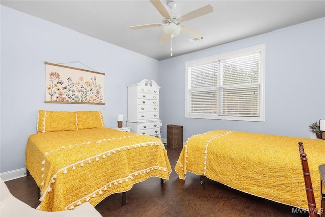 bedroom with a ceiling fan, visible vents, baseboards, and wood finished floors