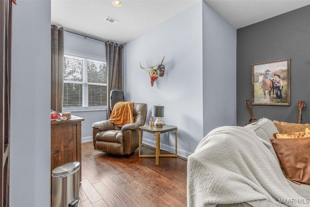 living area featuring dark wood-style flooring, visible vents, and baseboards