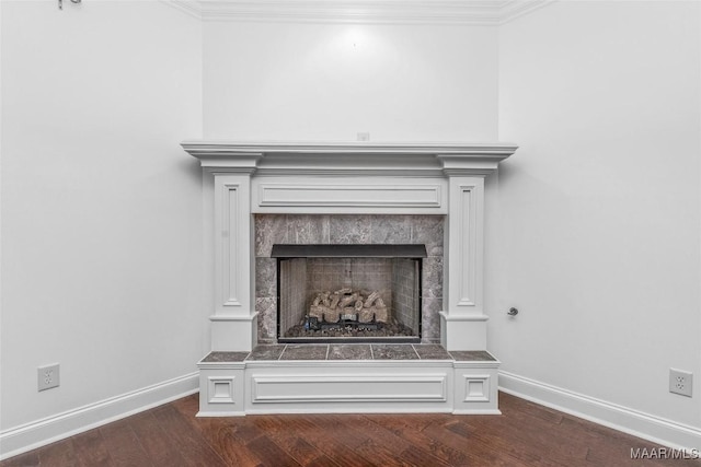 details featuring a tile fireplace, crown molding, baseboards, and wood finished floors