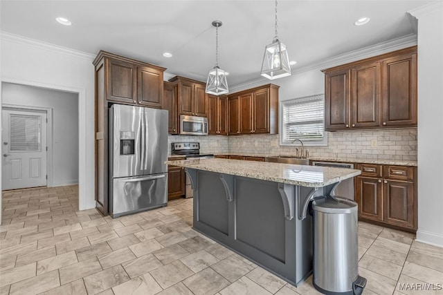 kitchen featuring stainless steel appliances, hanging light fixtures, a sink, a kitchen island, and a kitchen bar