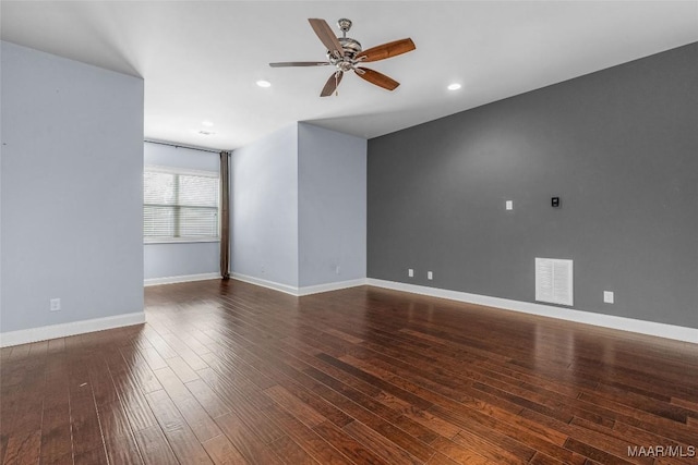 spare room with a ceiling fan, visible vents, dark wood finished floors, and baseboards