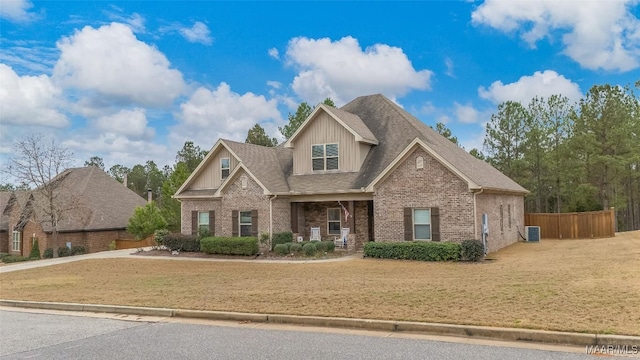 craftsman house featuring a front yard, brick siding, fence, and central AC unit