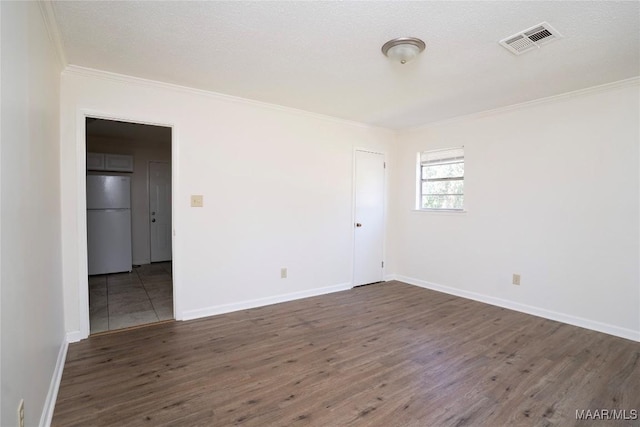 spare room featuring baseboards, visible vents, dark wood-type flooring, crown molding, and a textured ceiling