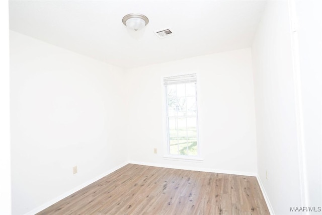 unfurnished room featuring light wood-type flooring, a healthy amount of sunlight, visible vents, and baseboards