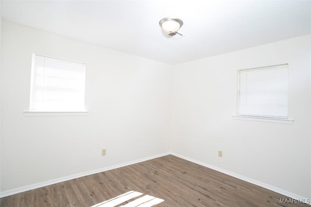 empty room with wood finished floors, visible vents, and baseboards