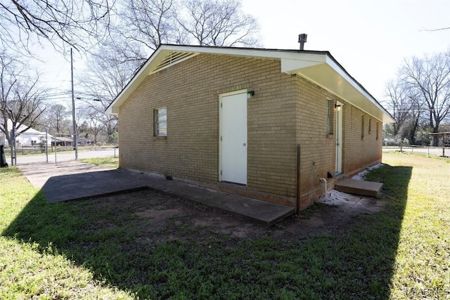 view of home's exterior with a yard, brick siding, and fence