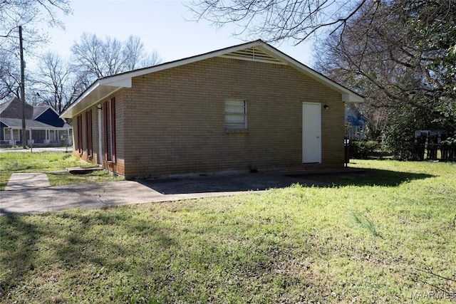 view of side of property with a patio area, brick siding, and a lawn