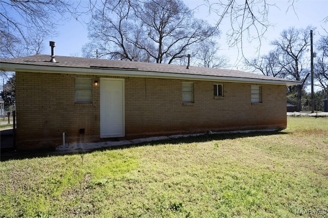 back of property featuring brick siding and a yard