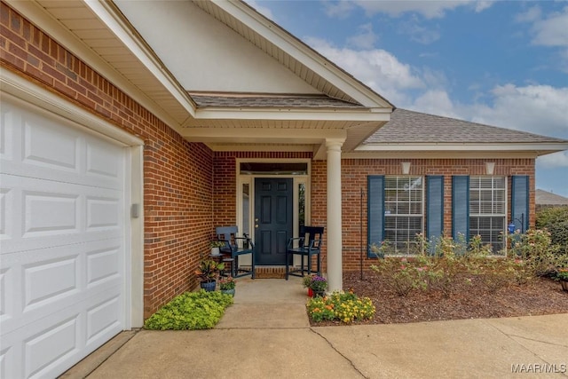 doorway to property with a garage, brick siding, and roof with shingles