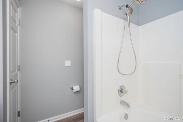 full bath with bathtub / shower combination, a textured ceiling, and baseboards