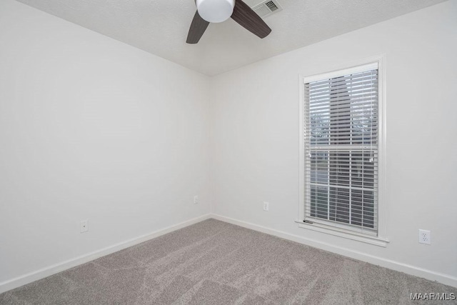 carpeted spare room featuring visible vents, ceiling fan, and baseboards