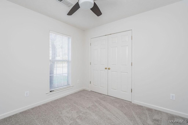 unfurnished bedroom featuring a closet, visible vents, light carpet, ceiling fan, and baseboards