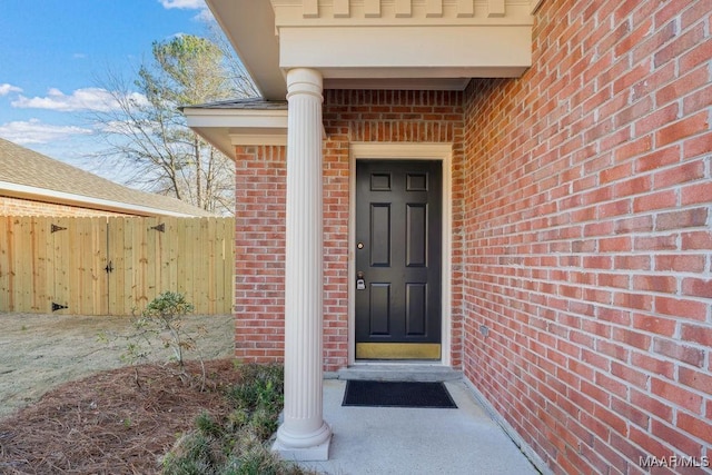 property entrance with brick siding and fence