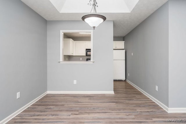 interior space with light wood finished floors, baseboards, and a textured ceiling