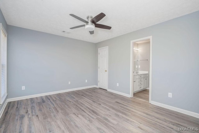 unfurnished bedroom featuring visible vents, a ceiling fan, ensuite bath, light wood-type flooring, and baseboards