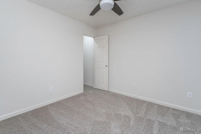 carpeted spare room with a ceiling fan and baseboards