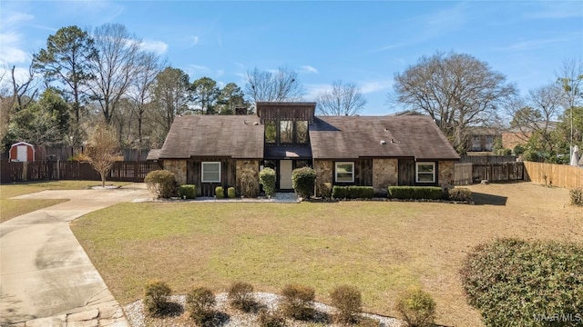 view of front of property with stone siding, fence, and a front lawn