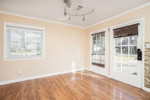 spare room with visible vents, baseboards, wood finished floors, rail lighting, and crown molding