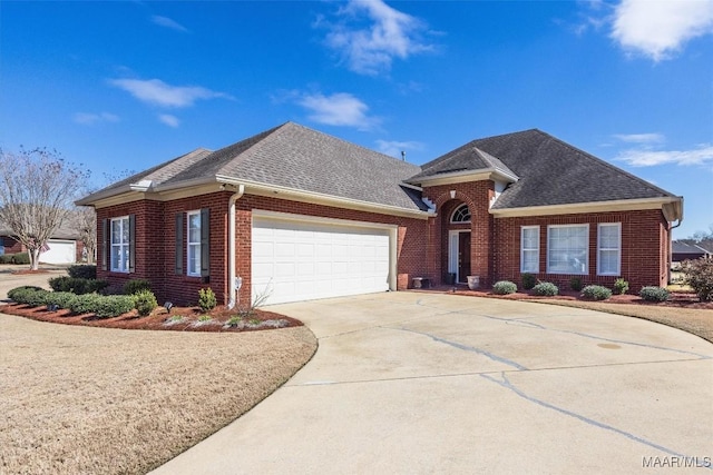 view of front of home with a garage, concrete driveway, brick siding, and roof with shingles