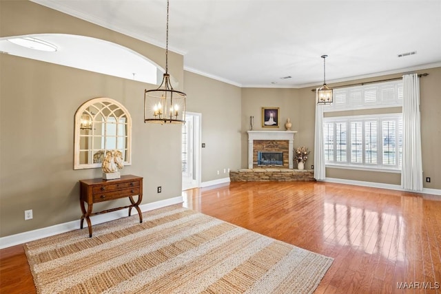 living room featuring crown molding, a fireplace, baseboards, and wood finished floors