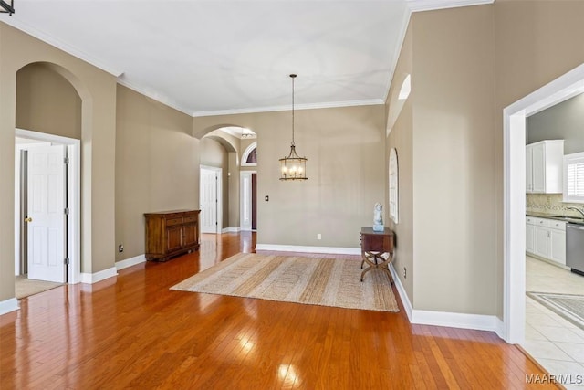 entrance foyer featuring light wood-style flooring, baseboards, and crown molding