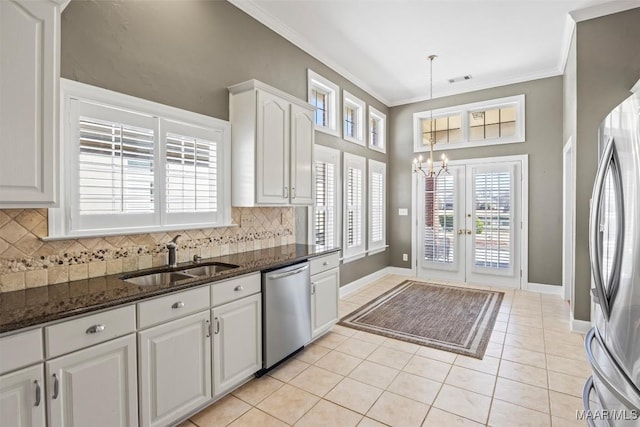 kitchen with a sink, white cabinetry, appliances with stainless steel finishes, dark stone counters, and crown molding