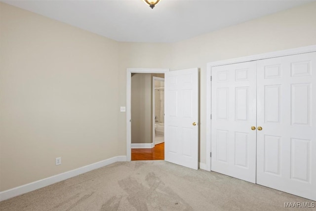 unfurnished bedroom featuring baseboards, a closet, and light colored carpet