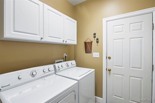 clothes washing area featuring cabinet space and separate washer and dryer