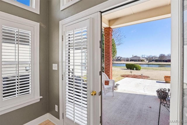 entryway featuring a water view, a wealth of natural light, and baseboards