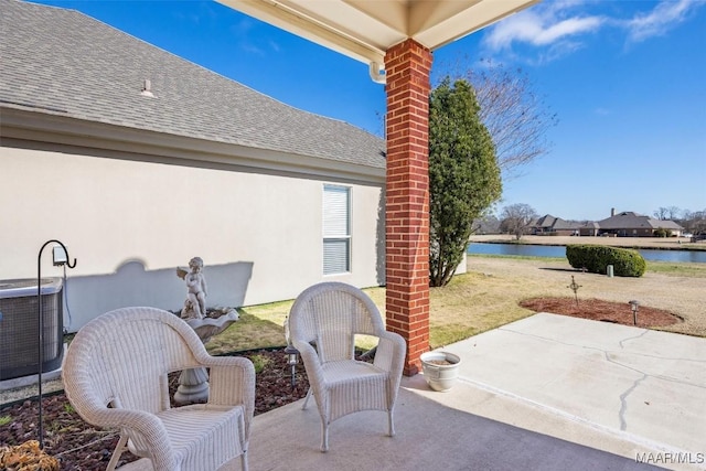 view of patio with central AC and a water view